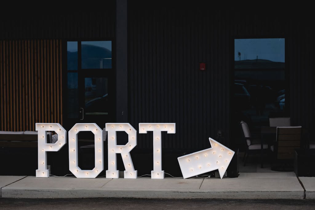 Illuminated PORT marquee letter rentals with a lighted arrow sign outside a corporate building at dusk