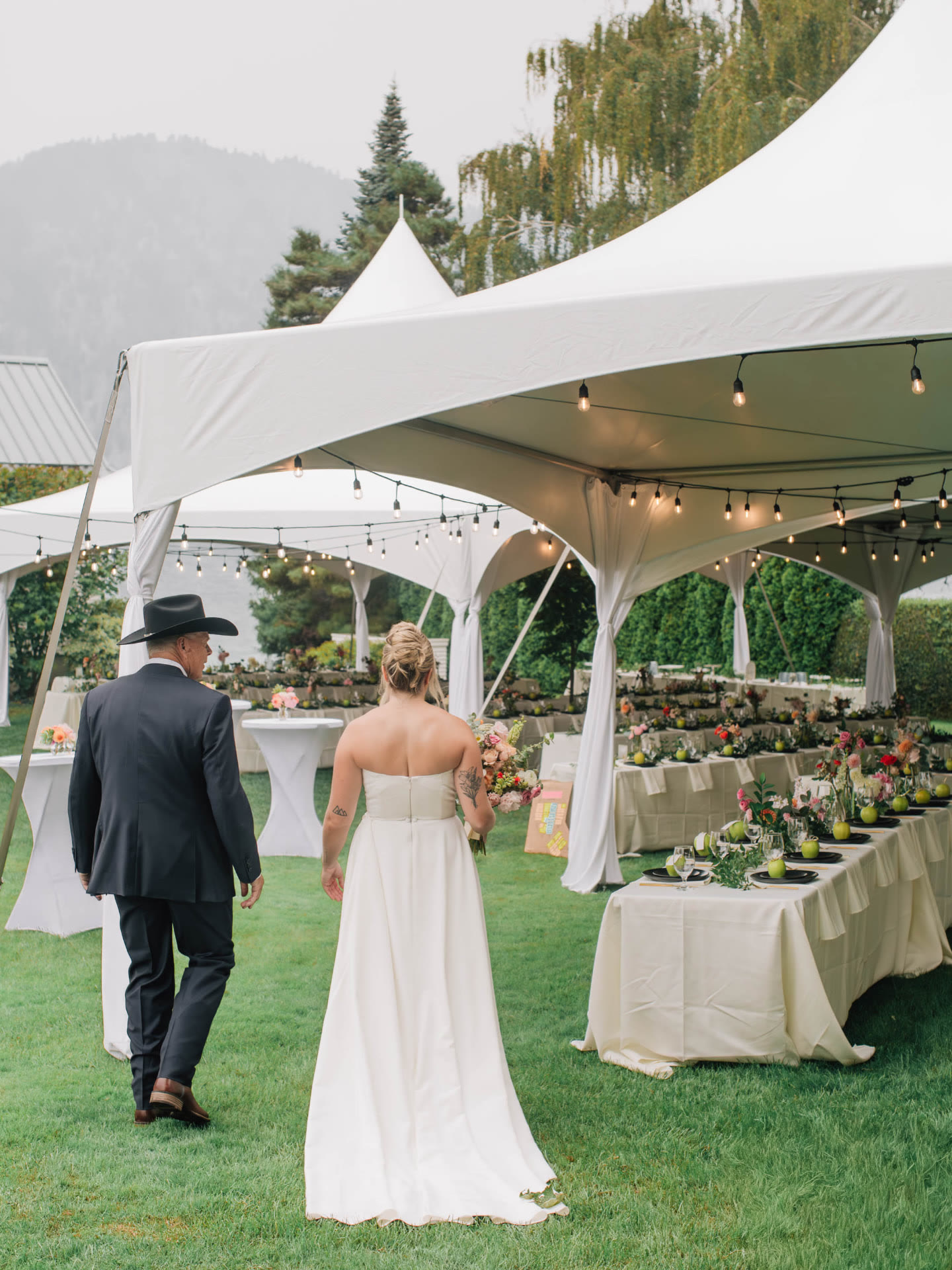 Banquet table rentals set family style under a marquee tent at a lakeside wedding reception in Eastern Washington