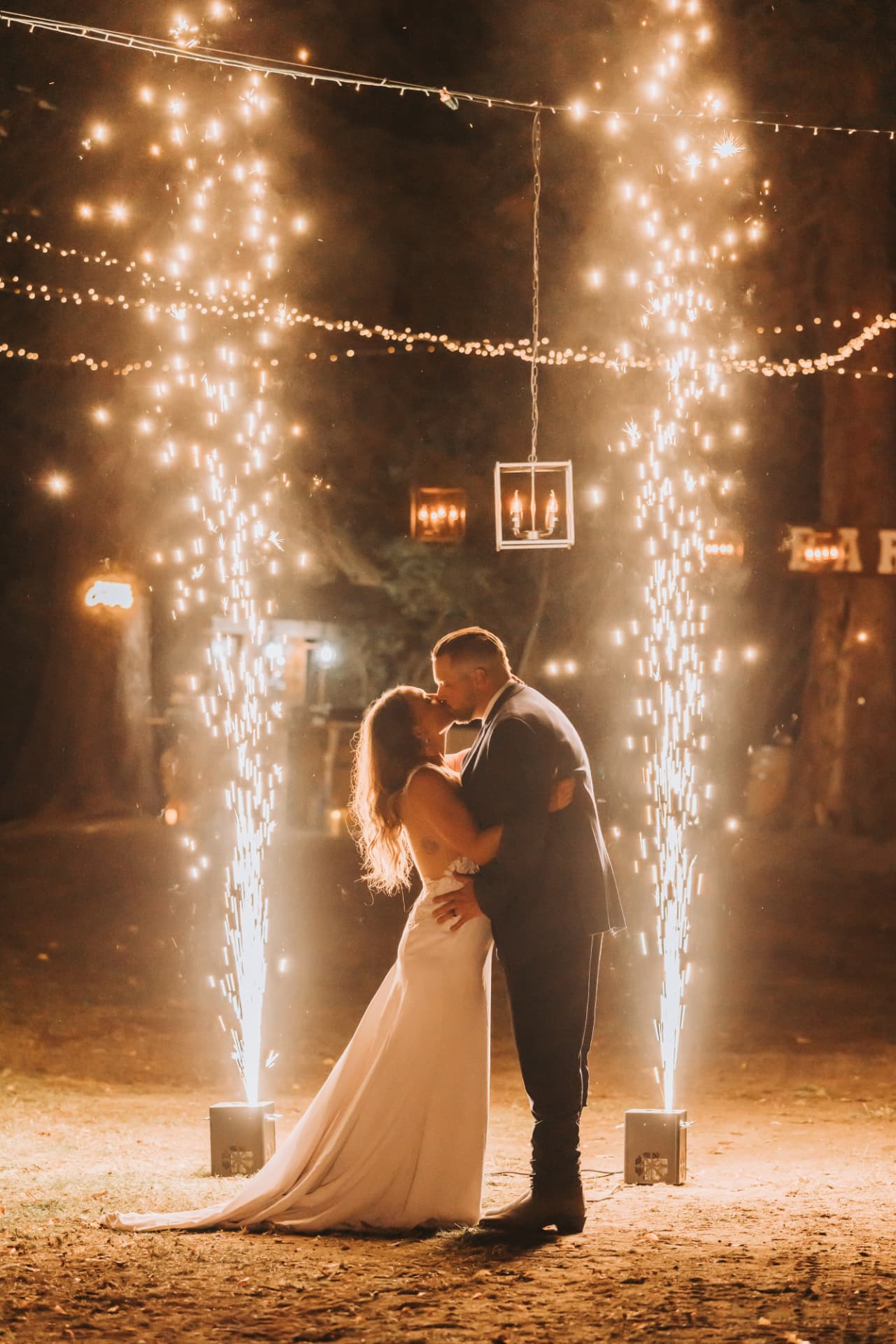 Newlyweds share a first kiss between two sparkler fountains at an outdoor evening reception set up by NCW Event Rentals in the Methow Valley
