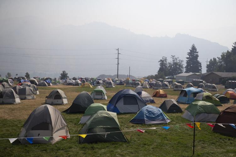 Firefighter tent city at a wildfire base camp near Chelan, Washington, with rows of crew tents on a field under smoky skies — the type of incident camp NCW Event Rentals supports with structures, flooring and equipment