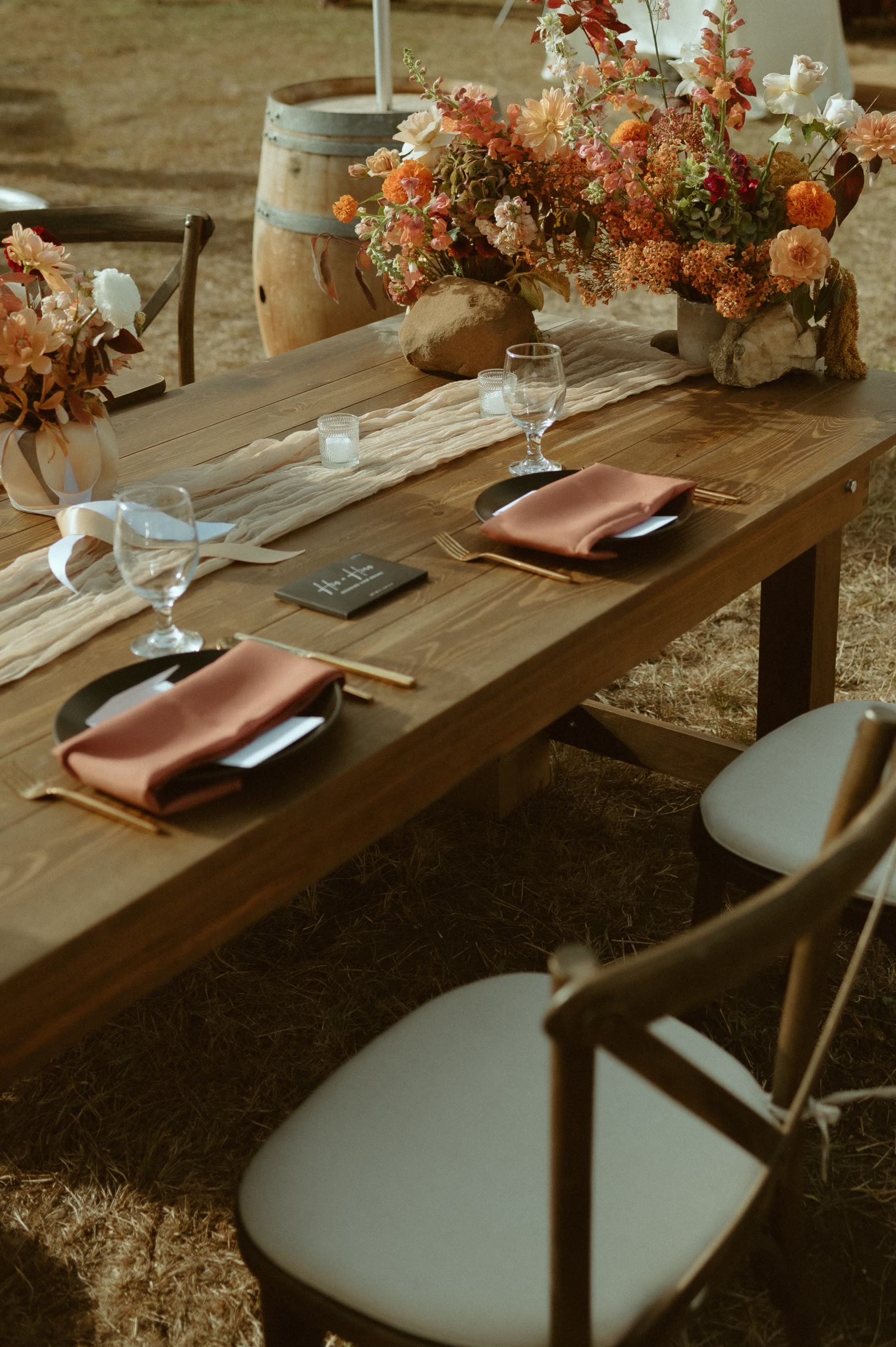 Gold flatware rentals set beside matte black plates and water goblets on a farm table with crossback chairs at a Washington wedding