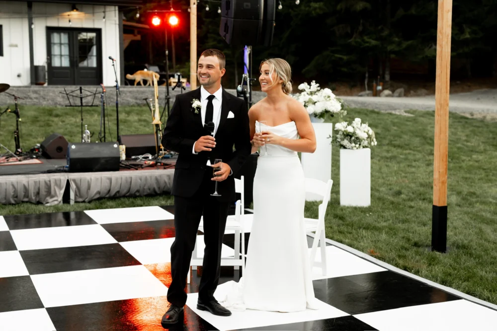 Dance Floor Rentals delivered by NCW Event Rentals in Cle Elum, Washington — Groom giving a speech on a black and white dance floor during an outdoor wedding reception in Cle Elum, Washington