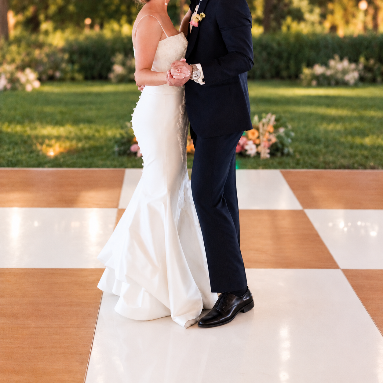 Bride and groom sharing their first dance on a 21x21 oak and white checkered dance floor at an outdoor garden wedding reception — dance floor rental from NCW Event Rentals in Eastern Washington