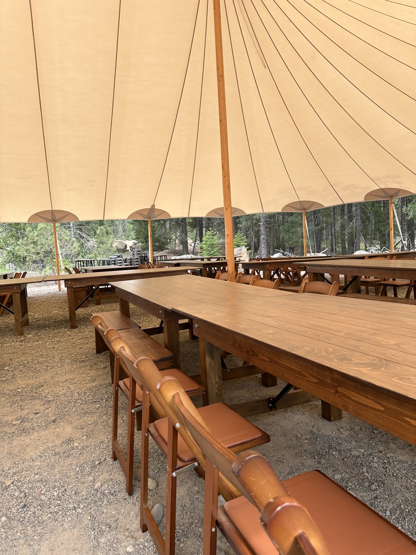 Rows of farmhouse tables and fruitwood folding chairs under a sailcloth tent at a Suncadia area event