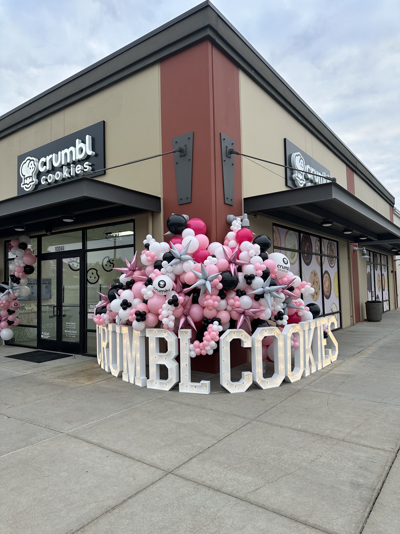 Giant lighted CRUMBL COOKIES marquee letters and a pink and black balloon installation at a retail grand opening in Eastern Washington