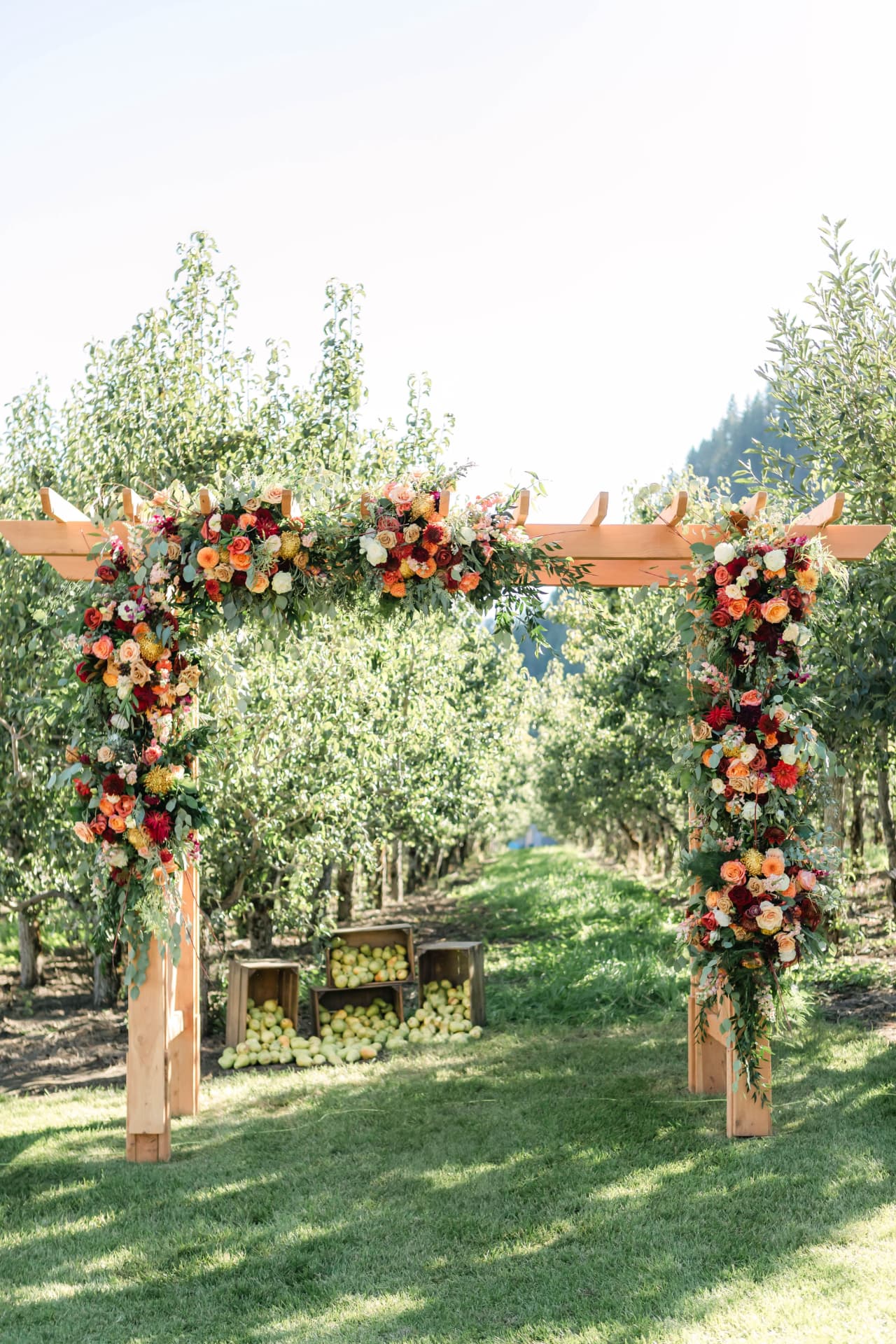 Wooden wedding arbor with fall floral arrangements set in an orchard ceremony site in Eastern Washington