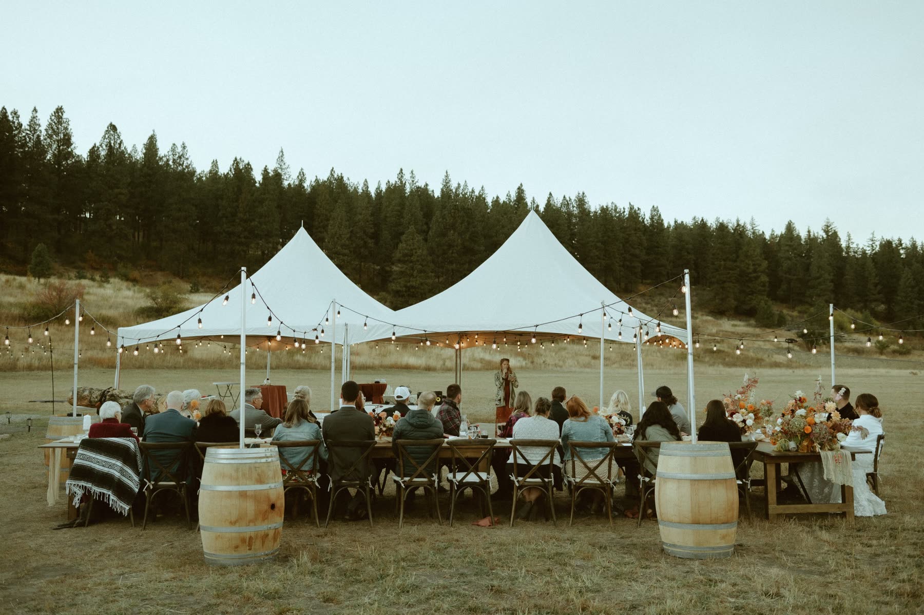 Farmhouse Table Rentals delivered by NCW Event Rentals in Tri-Cities, Washington — Farmhouse tables set for dinner under a sailcloth tent at a Washington wedding reception