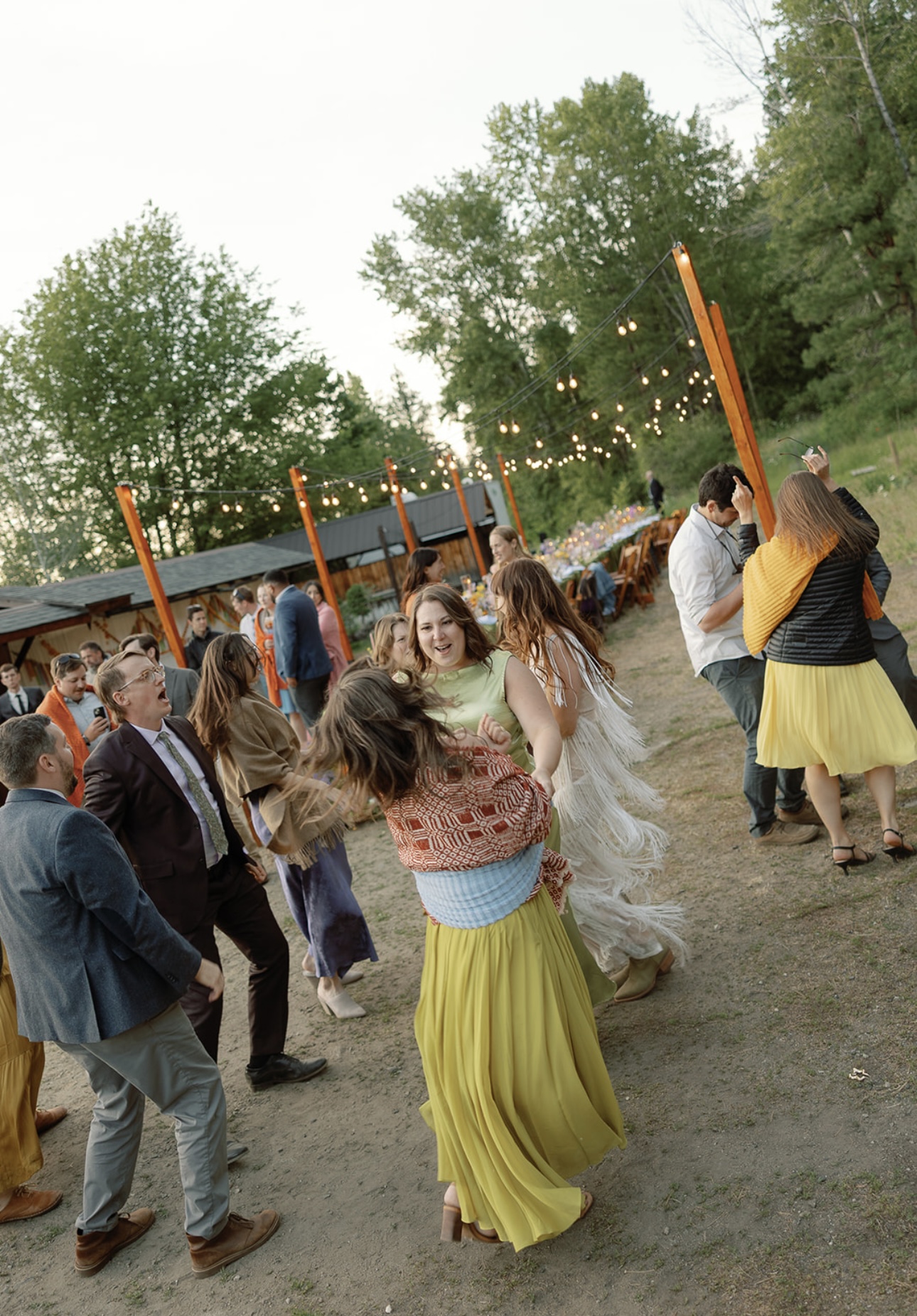 Wedding guests dancing under warm bistro string lights at an outdoor reception as evening falls in Eastern Washington