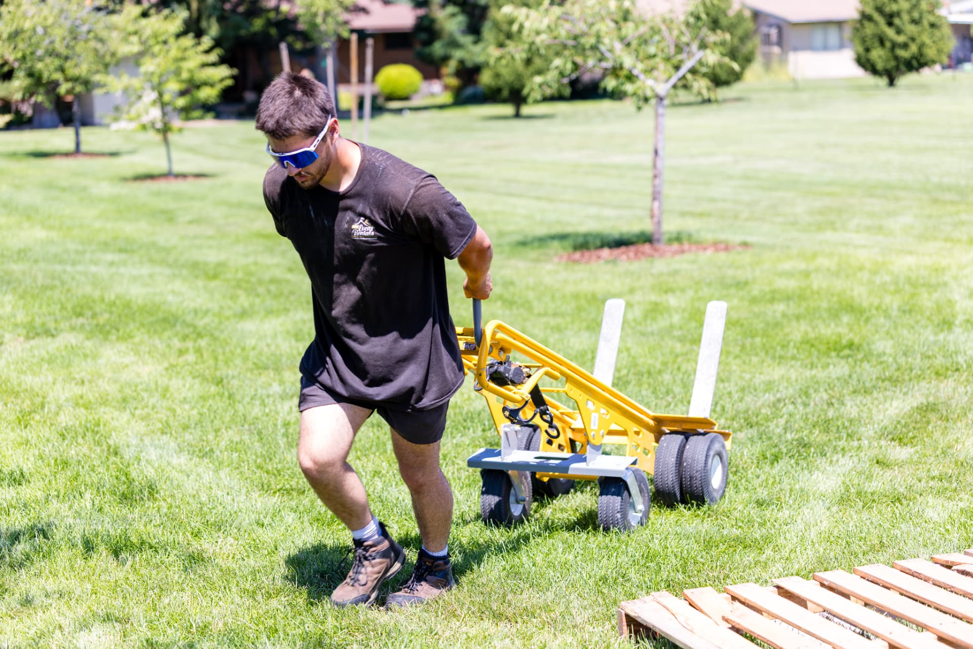 Crew member hauling a dance floor cart across a lawn during an event setup
