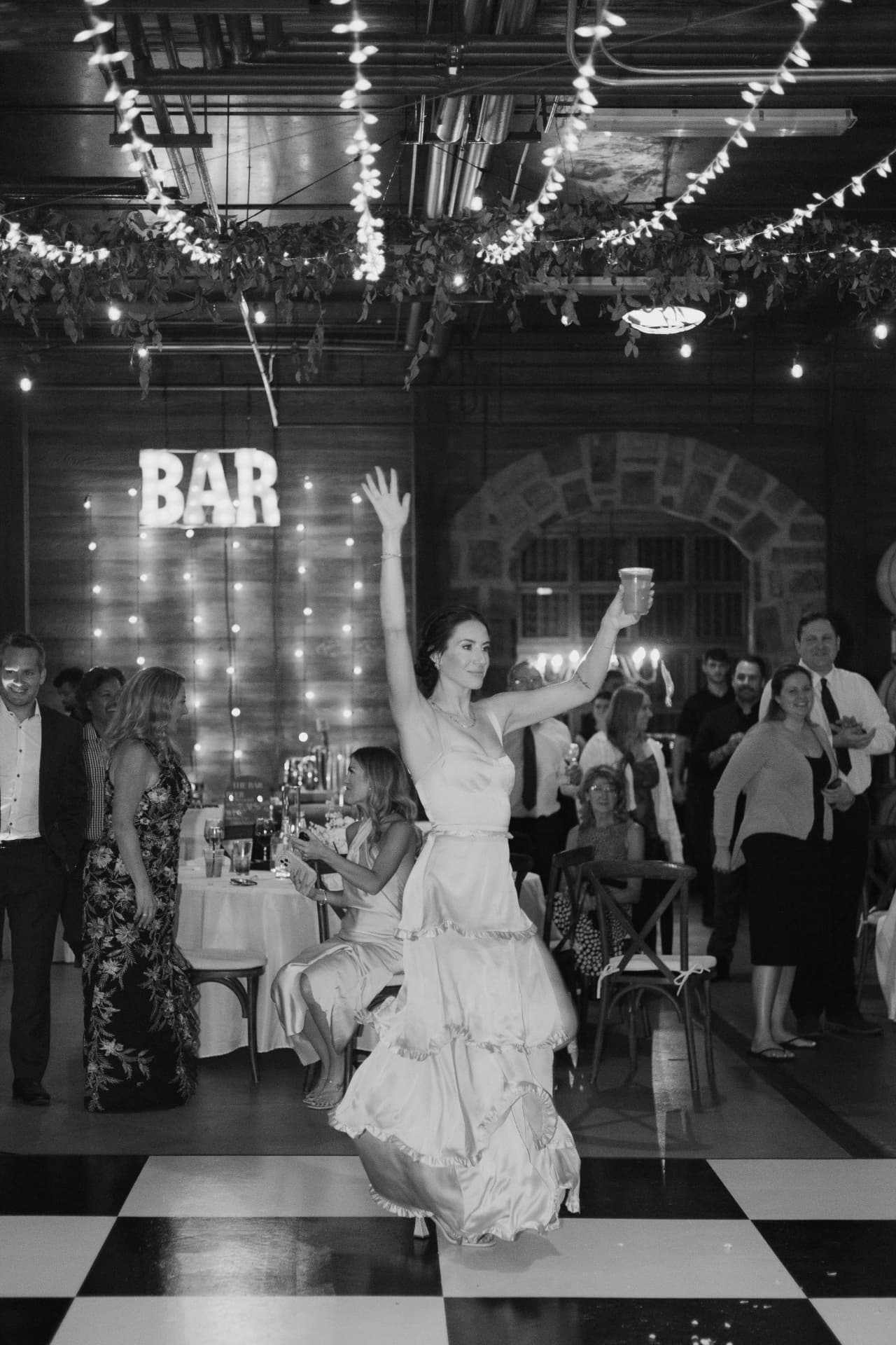 Wedding guest dancing under bistro string lights on a black and white dance floor rental at Swiftwater Cellars in Cle Elum, WA