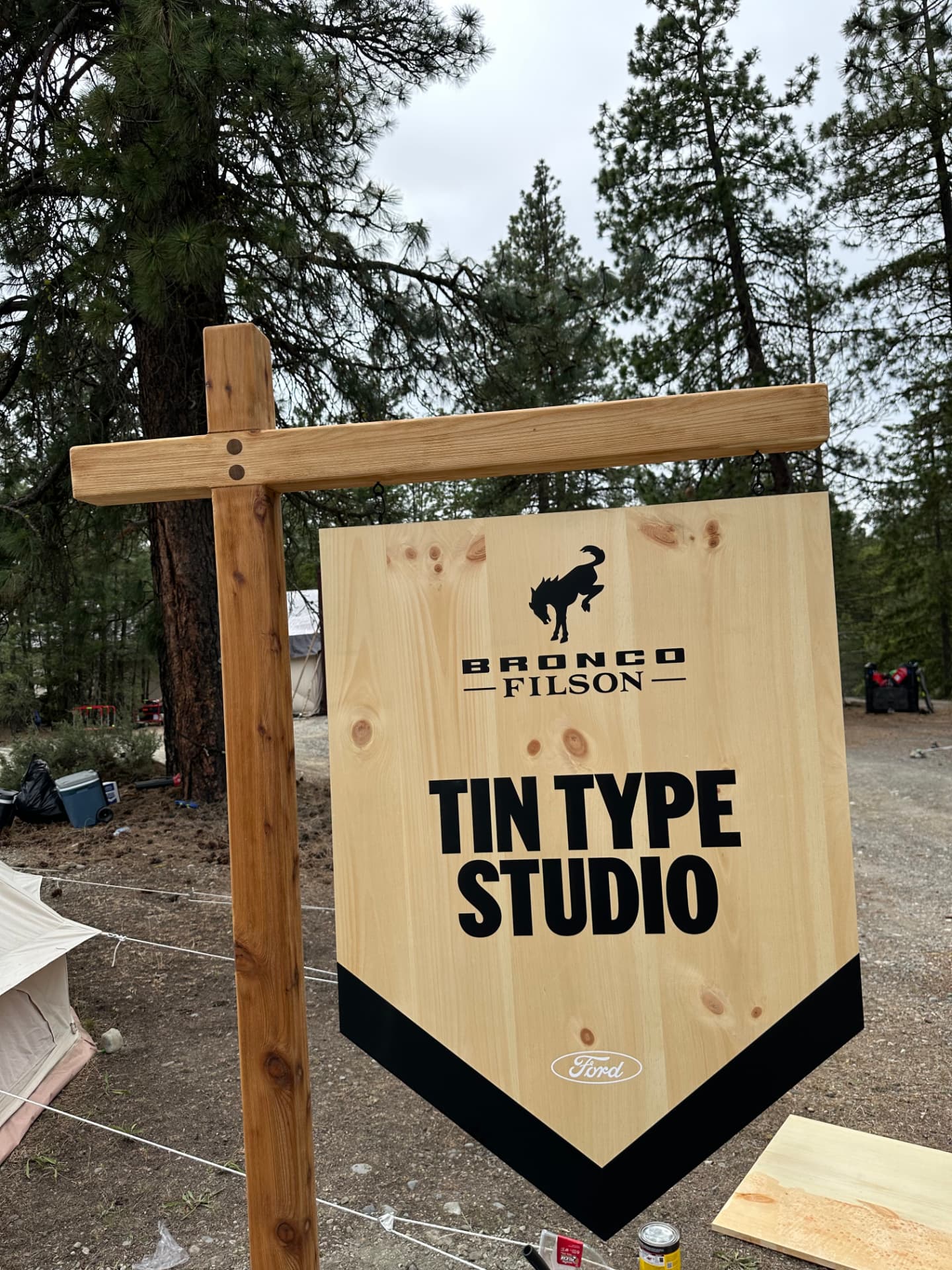 Ford Bronco and Filson brand activation at Suncadia Resort in Cle Elum, WA — a rustic tin type studio sign under a canvas tent in the pine forest, built by NCW Event Rentals