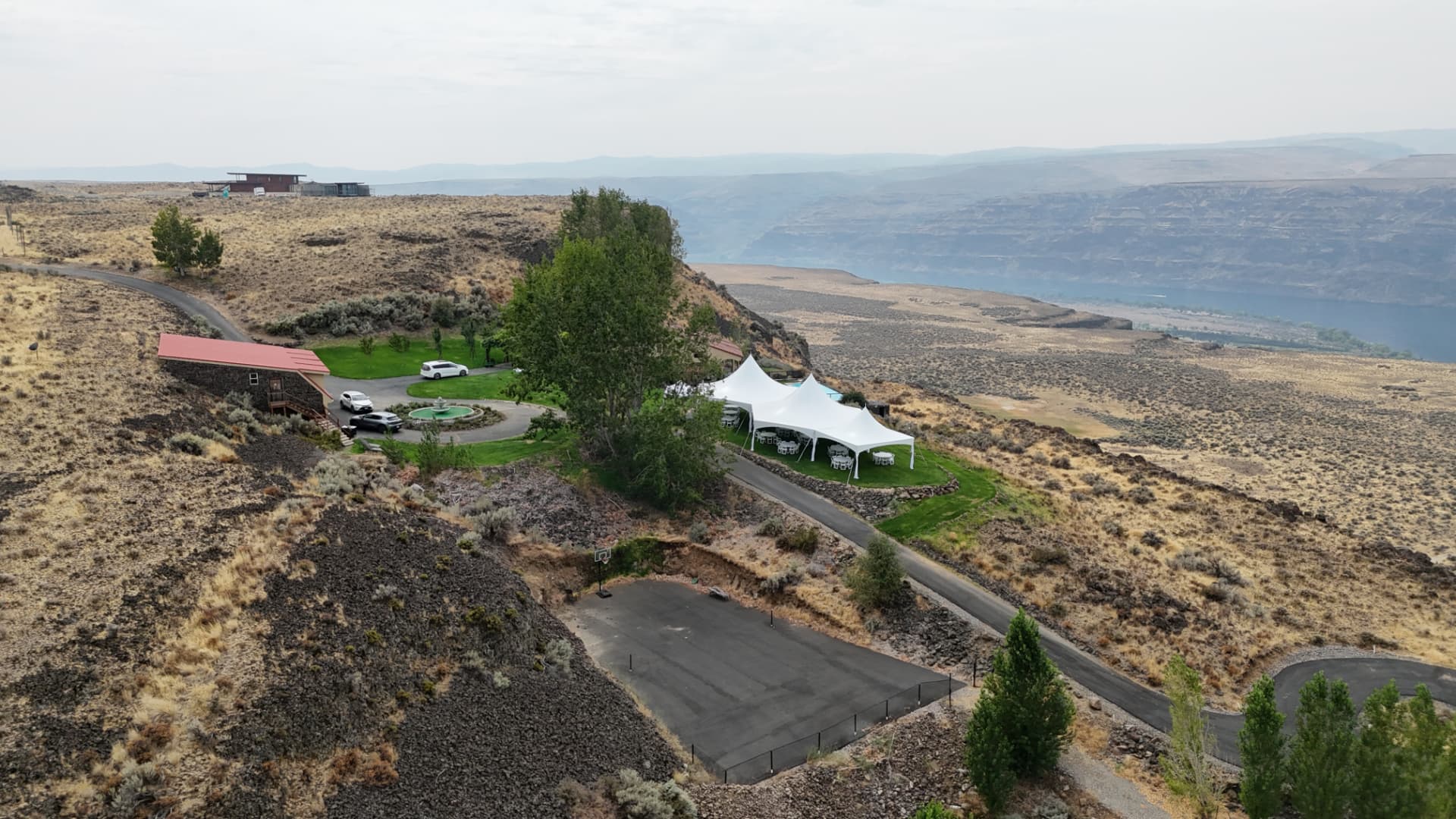 Aerial view of white high-peak marquee tents installed on a cliffside overlooking the Columbia River canyon in Eastern Washington