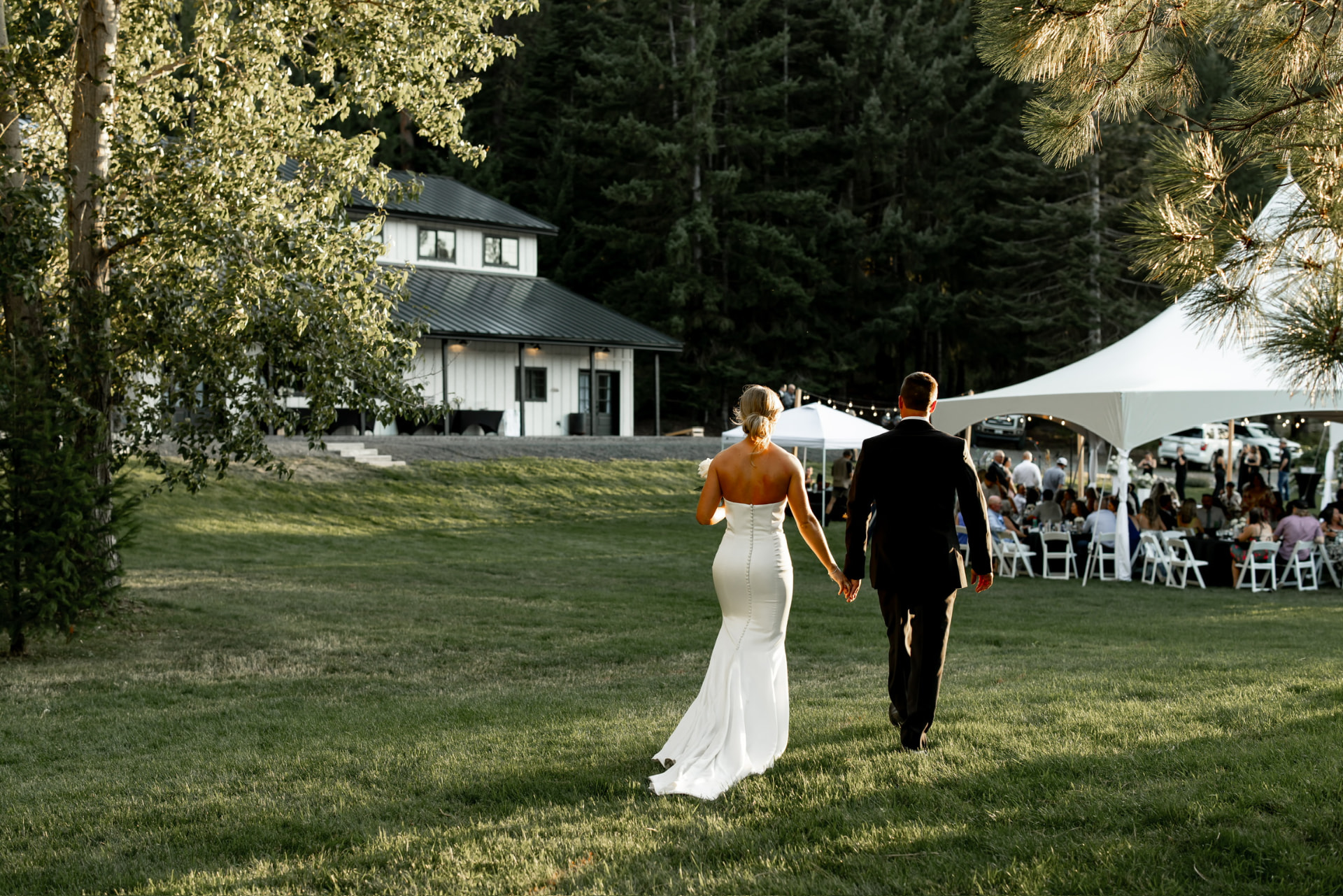 Bride and groom walking toward a large white reception tent rental in Eastern Washington