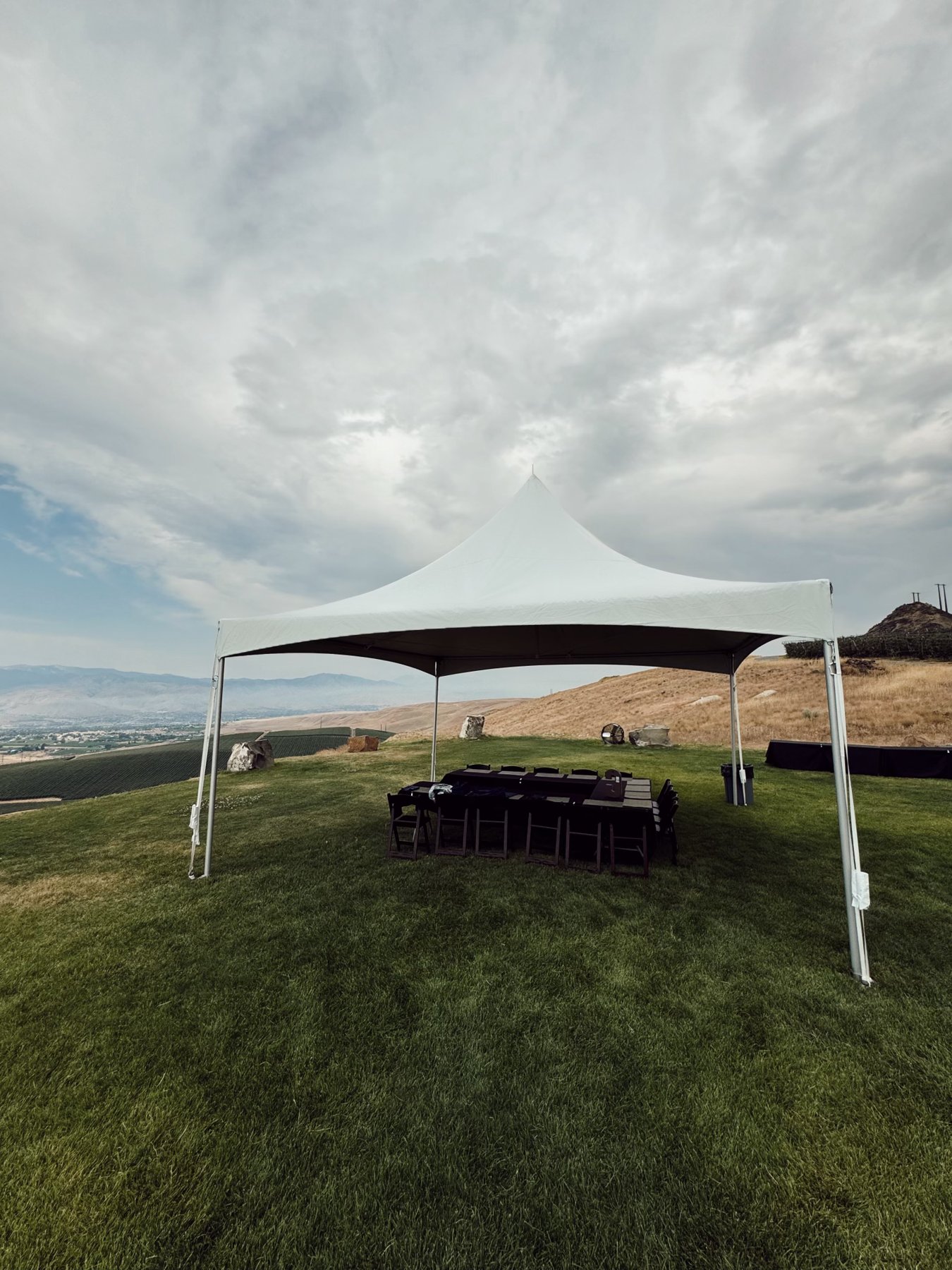 White 20x20 high-peak tent with a long executive dinner table overlooking vineyards and the valley at a hilltop corporate dinner